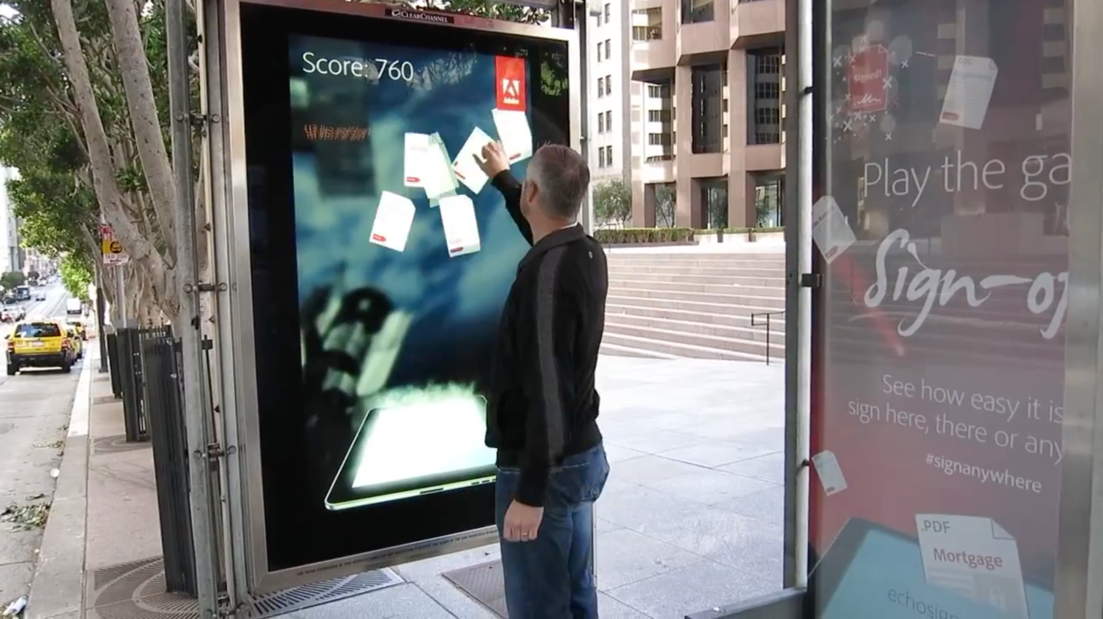 An on street interactive digital ad where a bystander is playing a game on it. There score is 760